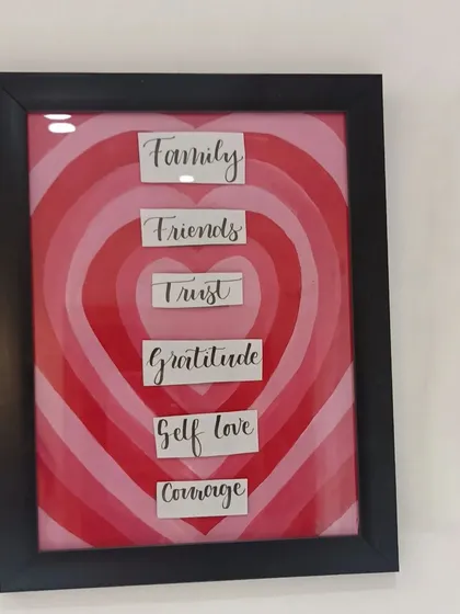 A custom wall frame I created with a layered heart design. It features words that are important to the client: Family, Friends, Trust, Gratitude, Self love, and Courage.