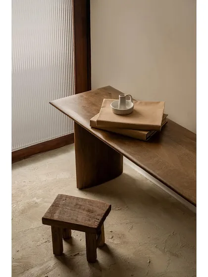 This vignette from the 'Crème' project highlights our focus on rustic and earthy details. A simple wooden bench and stool are set against a fluted glass partition, showcasing a wabi-sabi aesthetic of imperfect, natural beauty.