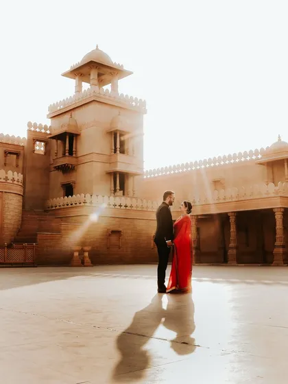 A grand courtyard sets the stage for this couple's story. The strong sunlight creates dramatic shadows, highlighting their connection against the timeless architecture in this regal pre-wedding portrait.