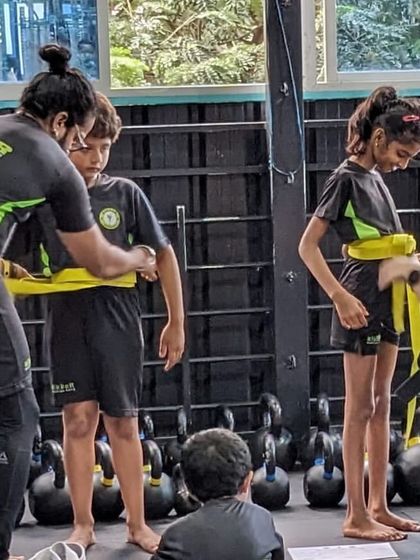 The moment a student earns their new belt is always special. Coaches helping tie the new yellow belts after a successful grading.