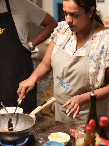 A participant fully engaged in the cooking process, learning to build layers of flavor in her dish during a weekend class.
