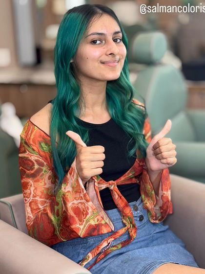 A happy client gives a thumbs-up for her new sea green hair. This vibrant fashion color is for anyone looking to express their personality and stand out from the crowd.