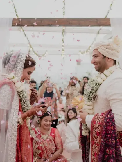 A shower of petals rains down on the couple during their varmala exchange, creating a beautiful and memorable photograph.