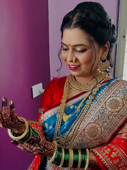 Admiring the intricate henna design. The bride's makeup is kept soft and radiant to let her happiness and traditional attire shine.