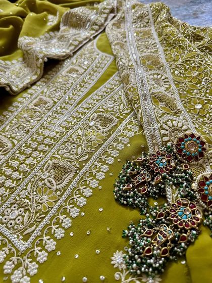 A flat-lay of the suit with traditional earrings, suggesting a complete occasion wear look.