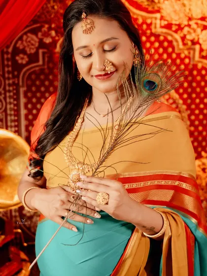 A close-up portrait capturing a quiet, reflective moment. The mother-to-be holds a peacock feather, a symbol of grace and beauty, adding a touch of traditional symbolism.