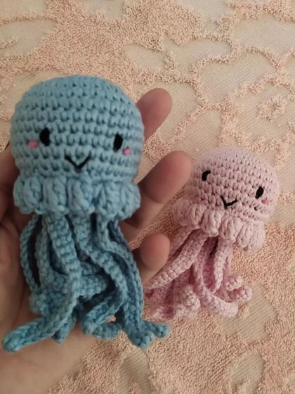 Holding the blue and pink jellyfish toys to show their cute, smiling faces and dangling tentacles.