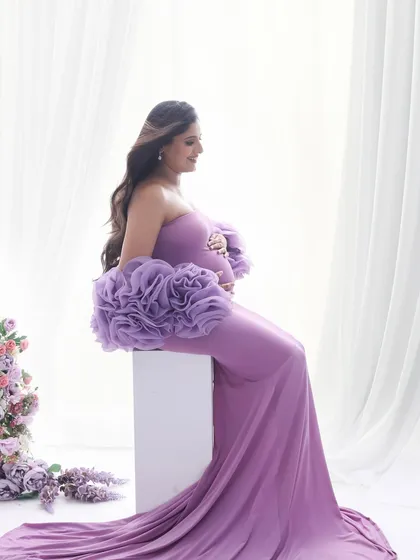 A serene side profile in a beautiful lilac gown. This pose elegantly showcases the baby bump while the soft fabric and color add a touch of romance.