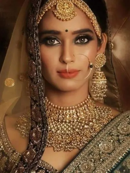 A classic, elegant bridal look. The model wears a heavy choker that perfectly complements her dark green, embroidered lehenga.
