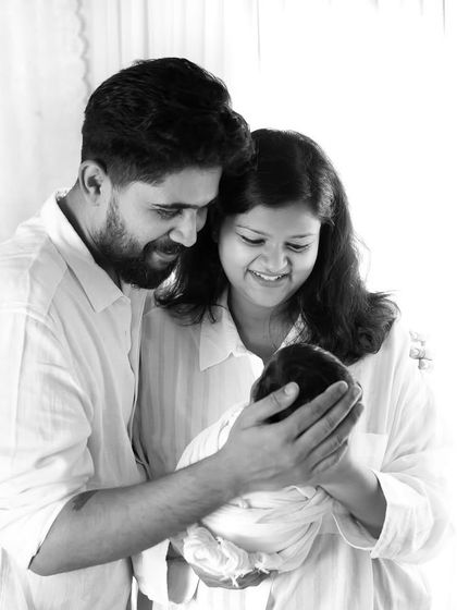 This is how you make memories that last forever. A beautiful, light-filled portrait of new parents gazing at their precious baby.