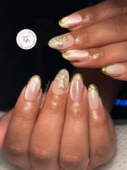 An elegant set featuring a milky white base with gold chrome French tips and delicate, hand-painted gold leaf accents.