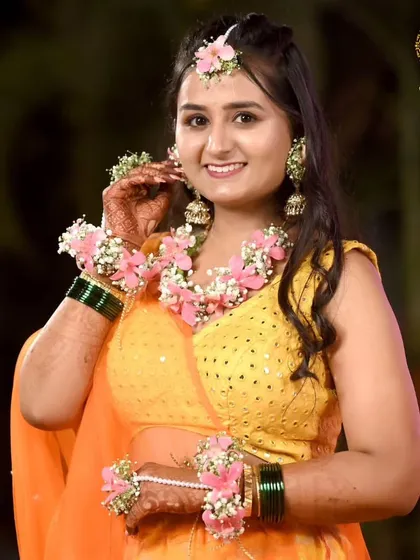 A smiling bride-to-be, looking lovely in her custom floral set. The combination of pink flowers and baby's breath is a timeless choice for a soft and romantic Haldi look.