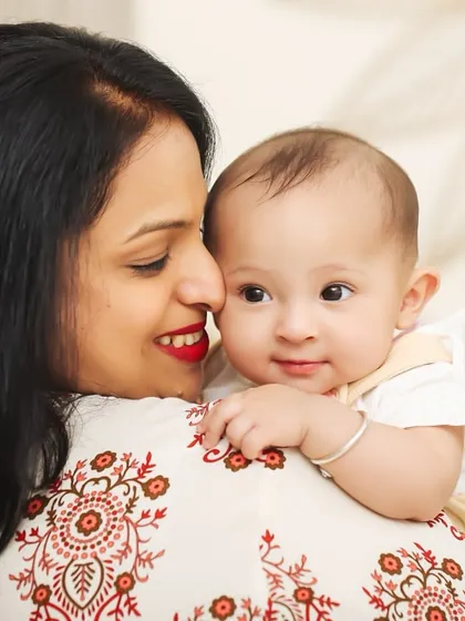 A sweet moment over the shoulder. This perspective captures the baby's curious gaze while still showing the mother's loving presence, creating a unique and intimate portrait.