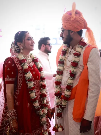 A sweet moment between the couple. The bride's classic look with a red lehenga and floral garland is timeless.