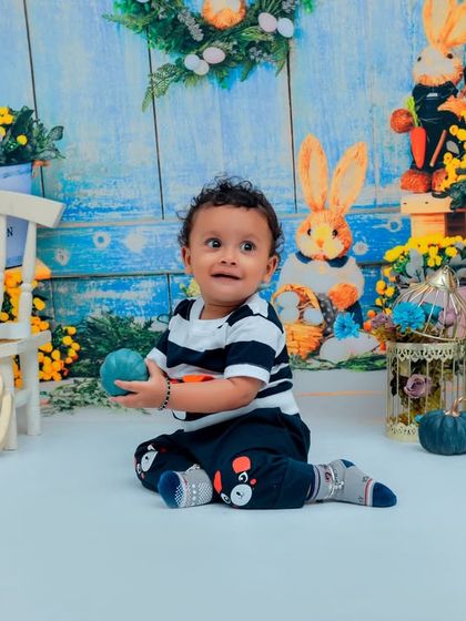 A candid moment from a first birthday shoot. This toddler is enjoying his time in our whimsical rabbit-themed set, complete with colorful props and a cheerful backdrop.