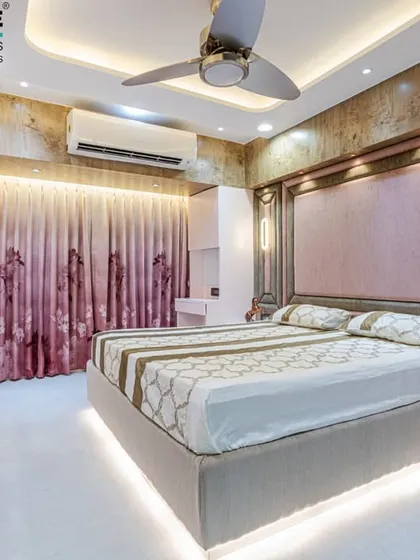 This bedroom in Seawoods features a luxurious pink upholstered headboard with vertical paneling and elegant wall sconces. The design creates a soft, romantic, and high-end feel.