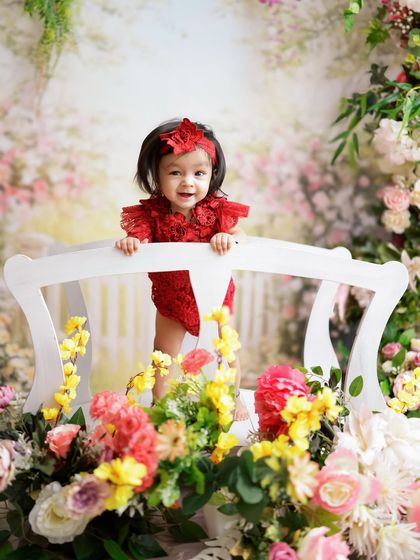 A little fairy in a secret garden. This beautiful floral setup with a white bench creates a dreamy and enchanting portrait.