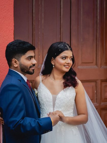 A candid moment of the couple holding hands against a bold red door. The composition and colors make this a striking and modern wedding portrait.