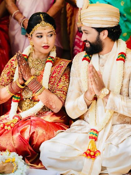 A bride and groom during their wedding ceremony. Her red and gold saree is a classic choice, perfectly complementing the sacred rituals.