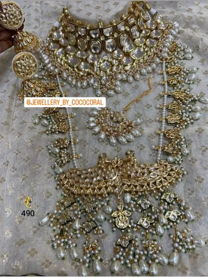 An absolutely regal bridal set featuring intricate Kundan work with pearl detailing. This rental set comes with a choker, a layered necklace, a passa, maang tikka, and matching earrings for a complete look.