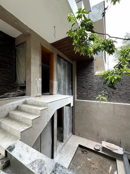 The entrance area of the DLF Phase 1 residence during construction, showing the interplay of different levels and the application of exterior stone cladding.