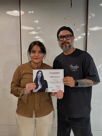 Certification is a major milestone. Here, a student proudly receives her certificate after completing an advanced haircut workshop with a visiting industry expert.