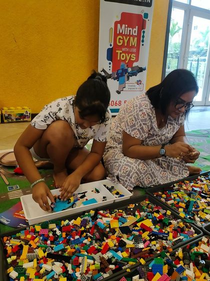 Two participants collaborate on a build, searching for the perfect pieces in a large bin of LEGOs. This shows the hands-on, exploratory nature of our learning environment.