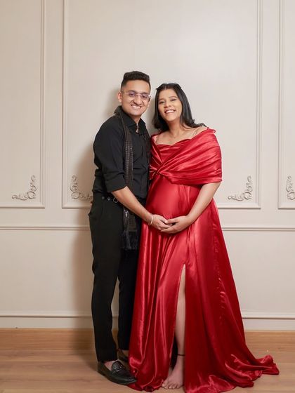 A happy couple portrait against a classic paneled wall in my studio. The 'Scarlet' gown's side slit adds a touch of glamour to this maternity photo.