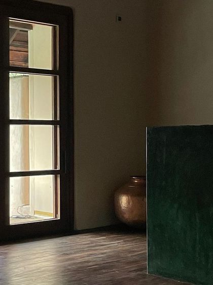 A quiet corner in the Malenadu House, where the warmth of the wooden door frame contrasts with the cool, smooth plaster walls.