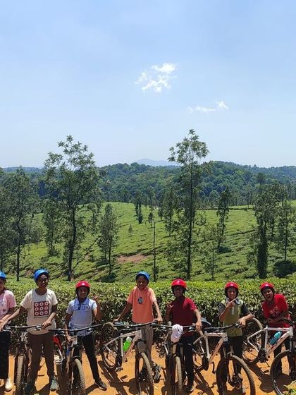 A team of young adventurers on their bikes, with the stunning landscape of Coorg stretching out behind them.
