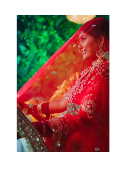 A dreamy shot of the bride through her red veil, creating a soft and romantic portrait that highlights her traditional look.