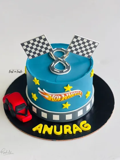 A Hot Wheels themed cake for a young racing fan. This design features a vibrant blue buttercream, the Hot Wheels logo, checkered flags, and a toy car.