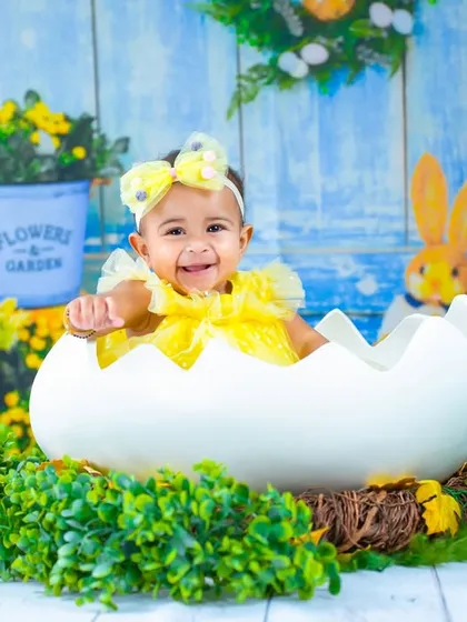 Posing happily in her Easter egg shell. The detailed backdrop with bunnies and flowers makes this a truly memorable spring portrait.