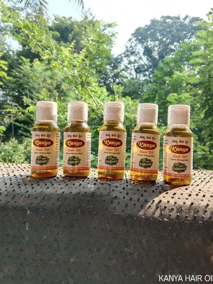 A line of Kanya Hair Oil bottles, showcasing the product against a natural background.
