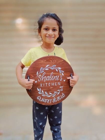 Our youngest fan holding the "Shalini's Kitchen" board. It fills our hearts to see our creations bring joy to the whole family.