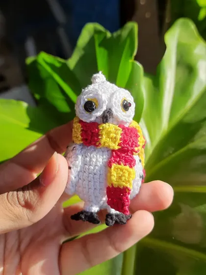 A straight-on look at the tiny Hedwig amigurumi. Her big eyes and striped scarf make her instantly recognizable, a magical companion for any Harry Potter fan.