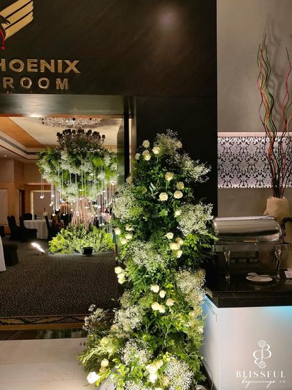 A slightly different angle of the ballroom entrance, highlighting the contrast between the dark, modern doorway and the fresh, vibrant floral decor.