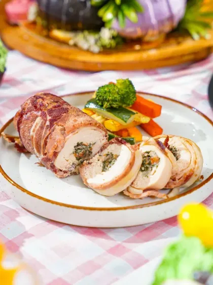 Slices of a savory meat roulade served on a plate as part of an Easter brunch. The checkered tablecloth and surrounding festive dishes create a complete holiday dining scene.