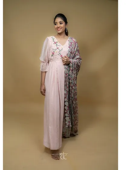 A graceful blush pink floor-length dress, perfect for any festive occasion. The delicate thread embroidery on the bodice is complemented by a beautifully printed scalloped georgette dupatta.