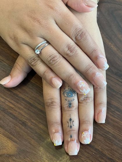 A clear, still image displaying the finished natural-look manicure with delicate floral art. It's a perfect example of how we can enhance your natural nails with subtle, artistic details.