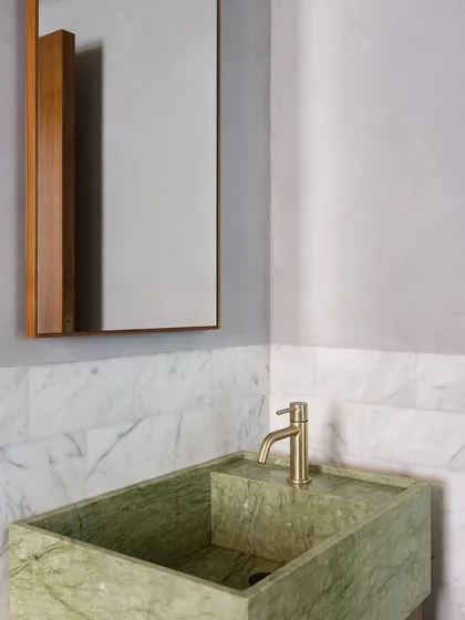 A powder room with a custom basin carved from green marble. I designed this piece to have a unique, stepped form, turning a simple sink into a sculptural object.