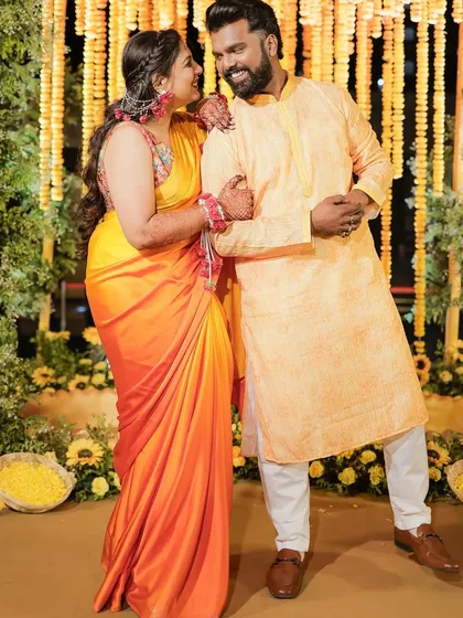 A full-length shot of the couple at their Haldi ceremony, surrounded by beautiful marigold decorations.