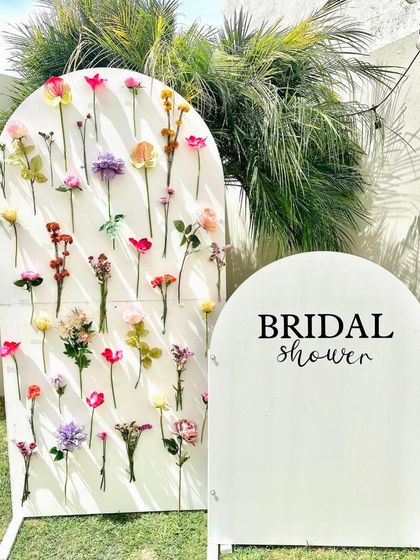 A minimalist and modern bridal shower setup with a flower wall backdrop, perfect for an outdoor celebration.