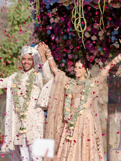 The triumphant "we did it" moment! Raising their hands in celebration after the varmala, showered in petals by their loved ones. This is the energy I love to see at my weddings.
