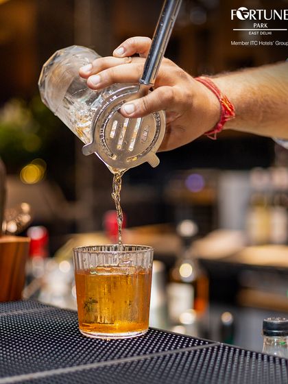 The art of mixology on display. A bartender carefully pours a classic cocktail, showcasing the precision and skill behind every drink we serve.