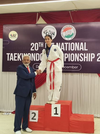A student stands proudly at the number one spot on the podium after winning gold in individual sparring at the 20th National Taekwon-Do ITF Championship.