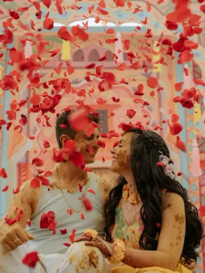The pure, unadulterated joy of a Haldi ceremony, with the couple laughing as they are showered in a rain of red rose petals.
