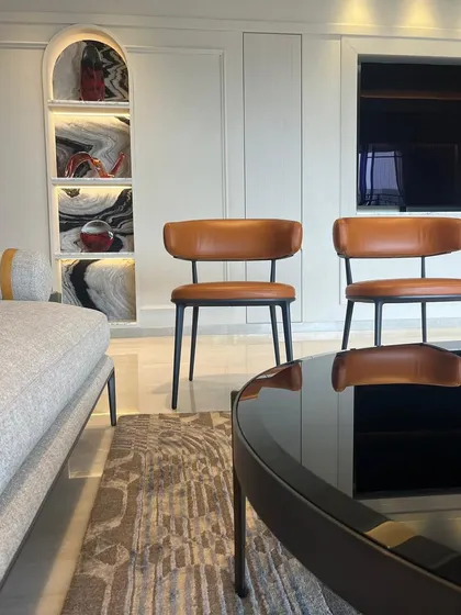 This space showcases a modern classic aesthetic, featuring iconic B&B Italia leather chairs. The arched display niche with its dramatic marble-effect back adds a touch of architectural elegance.