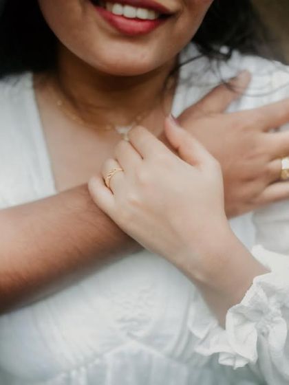 A close-up on the couple's embrace, focusing on their intertwined hands and rings. This detail shot highlights their connection amidst the natural setting.