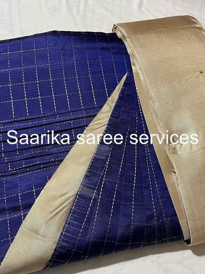 A modern blue checked saree with a plain beige border. The pleats are set to maintain the geometric pattern.